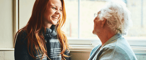Young white women in scarf smiling at mature white woman