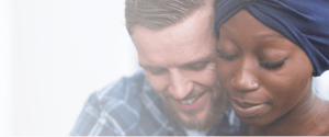 woman with cancer next to smiling male partner on white background