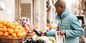 woman shopping for fruit and vegetables holding an aubergine
