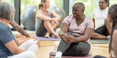 women sitting on mats in a gym class