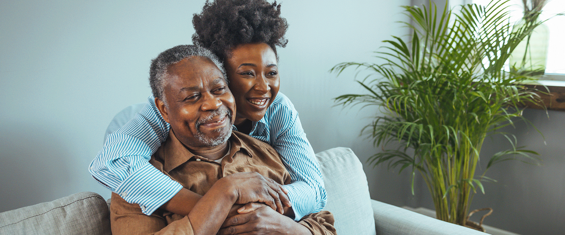 daughter wrapping her arms around father with cancer's shoulders